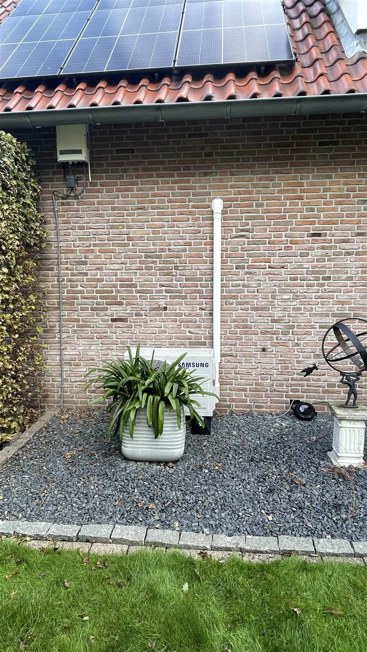Samsung buitenunit tegen de gevel van een woning met zonnepanelen, geplaatst door De Neut Techniek