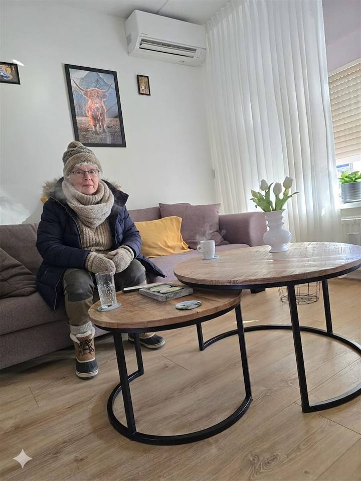 Bewerkte grapfoto: bewoonster met jas en sjaal onder een Panasonic airco in een woonkamer in