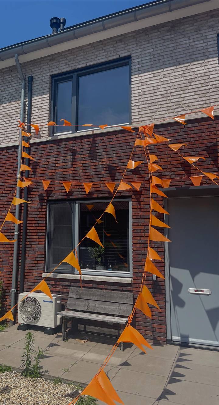 Panasonic buitenunit voor een rijwoning in Zwolle, naast een houten bank
